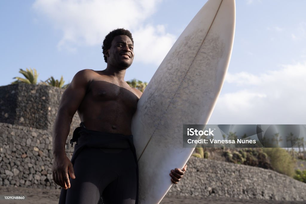 Surfer african american man holding long board before surf session - Extreme sport lifestyle Surfer african american man holding longboard before surf session - Extreme sport lifestyle Tenerife Stock Photo