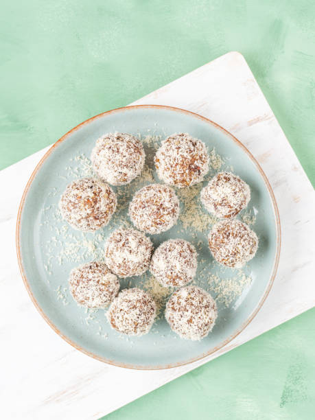 Home made energy protein balls with coconut flakes and nut butter Home made vegan energy protein balls with coconut flakes, almond butter, oats, nuts, dates, dried fruit, flax and hemp seeds served on white wooden board. plasma ball stock pictures, royalty-free photos & images