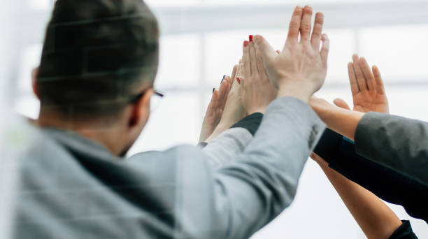 istock close up. a group of young employees giving each other a high five 1329256850