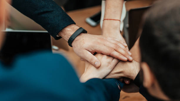 istock close up. business team folding their palms over the Desk 1329256941