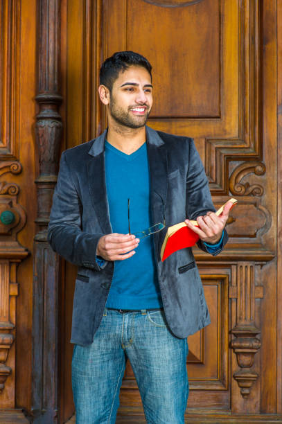 istock Young Man standing by office door, reading red book 1329259605