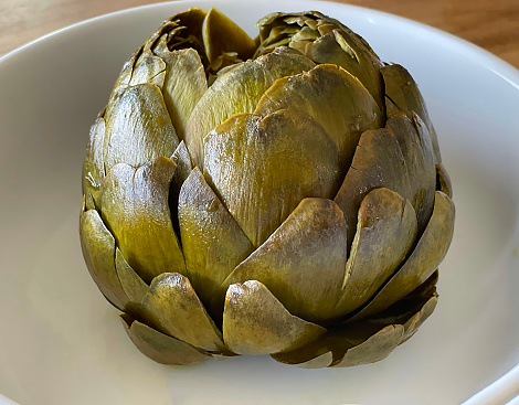A closeup shot of five artichokes on a wooden board isolated on a white background