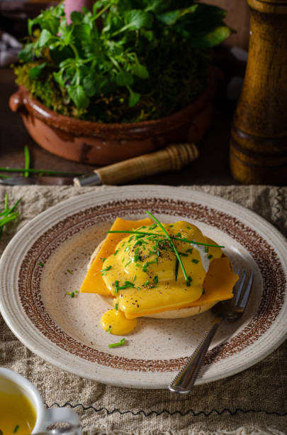 Delicious eggs benedict Organcic eggs benedict with bacon, cheddar cheese and herbs and hollandaise sauce hollandaise sauce stock pictures, royalty-free photos & images