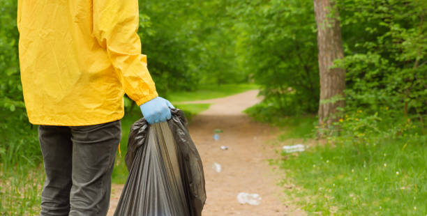 istock Volunteer cleaning up garbage a forest. People care earth pollution plastic garbage worker hand holding trash bag. Go green. Banner volunteer hands picks up a plastic trash grass in park. Eco friendly 1329268102