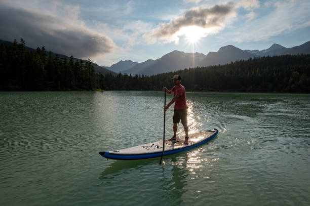 istock Man stand up paddle boarding on a pristine mountain lake 1329268103