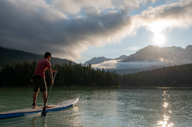 istock Man stand up paddle boarding on a pristine mountain lake 1329268105