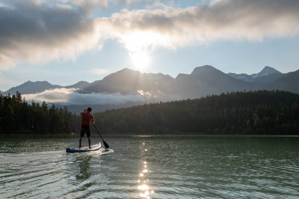 istock Man stand up paddle boarding on a pristine mountain lake 1329268109