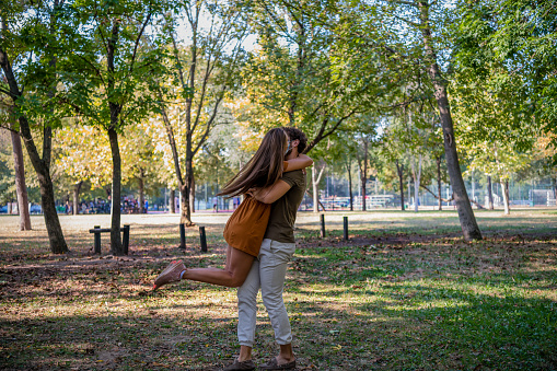 A Young Bearded Man and his Wife are Hugging in the Public Park and Sharing Lovely Emotions During a Relaxing Work in the Pandemic Time.