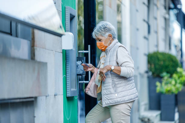 istock An Older Woman with Face Mask is Using ATM. 1329270645
