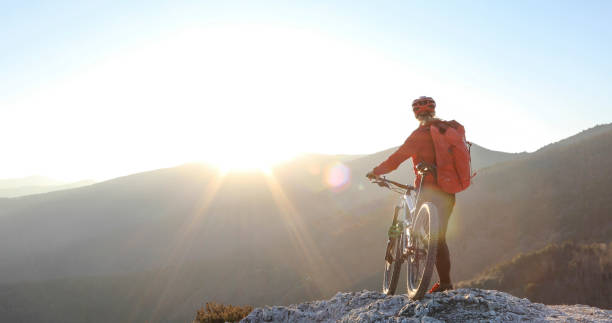 istock Female mountain biker relaxes on mountain ridge at sunrise 1329270683