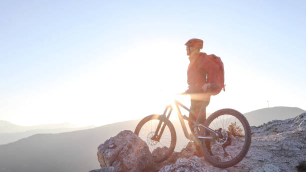 istock Female mountain biker relaxes on mountain ridge at sunrise 1329270690