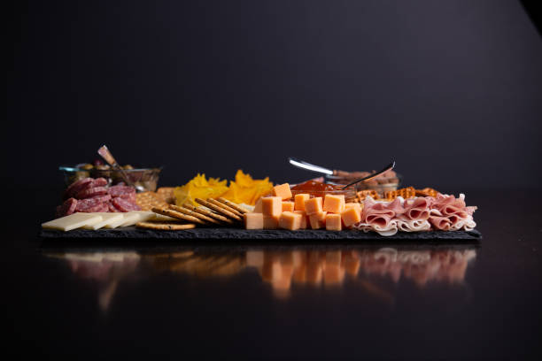 Full platter with meats, cheese, nuts, crackers and an apricot spread. Enjoying a gourmet cheese board appetizer for a holiday celebration charcuterie stock pictures, royalty-free photos & images