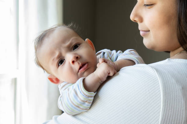 istock Adorable baby makes a face at the camera while his mother holds him 1329284947