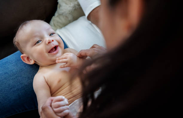 Happy newborn baby smiles at mother while she holds him Happy newborn baby smiles at mother while she holds him 8 weeks stock pictures, royalty-free photos & images