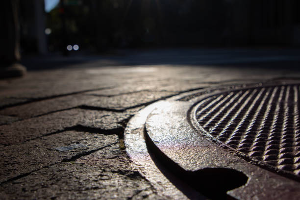Sunset casts shadow on sidewalk and manhole cover stock photo