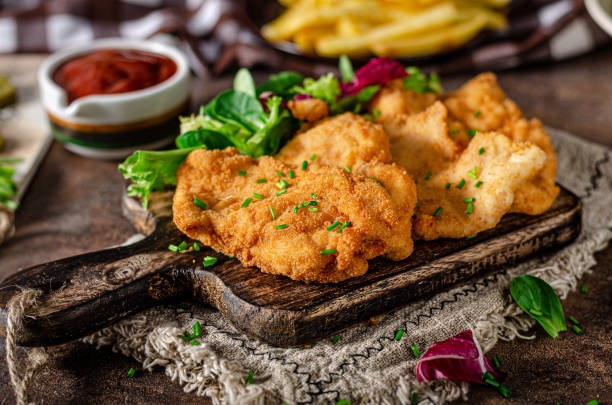 Delicious original schnitzel Tender schnitzel with fresh salad, tomatoes and french fries breaded photos stock pictures, royalty-free photos & images
