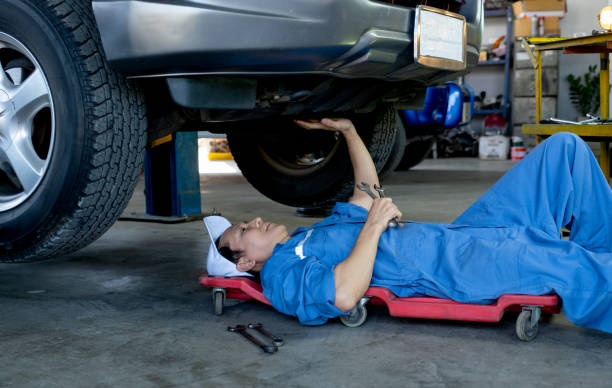 istock Technician or garage worker lie down under the car and touch also looking area to fix the problem in workplace 1329295327
