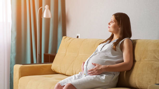 istock Young pregnant woman stroking belly while sitting on the sofa 1329302810