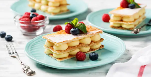 Classic french dessert millefeuille with vanilla cream and fresh berries.