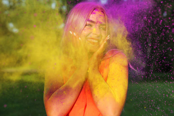 istock Expressive young model posing with exploding yellow paint at summer Holi festival 1329307642