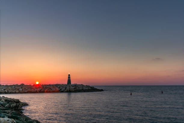 日没時のテルアビブの港の入り口にある小さな灯台 - sailboat sunset tel aviv sea ストックフォトと画像
