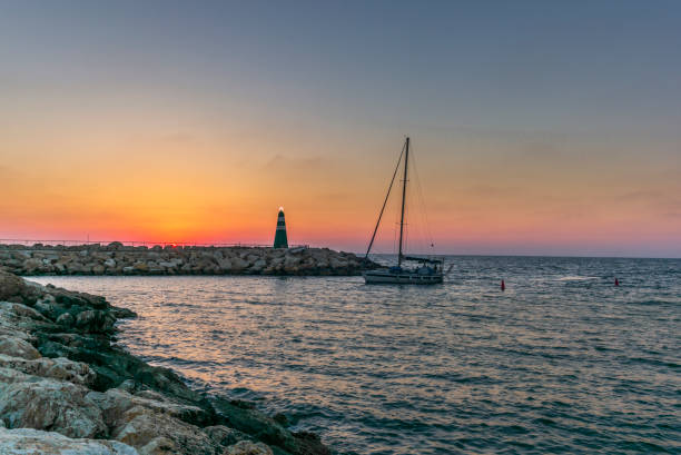 a lonely sailingboat returning to the harbour in tel aviv at sunset - sailboat sunset tel aviv sea imagens e fotografias de stock