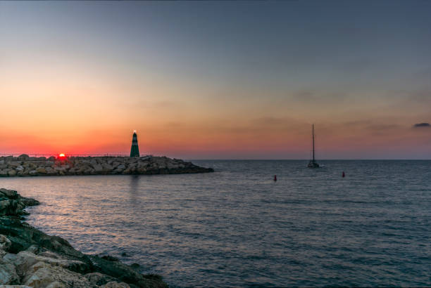 日没時にテルアビブの港に戻る孤独なセーリングボート - sailboat sunset tel aviv sea ストックフォトと画像