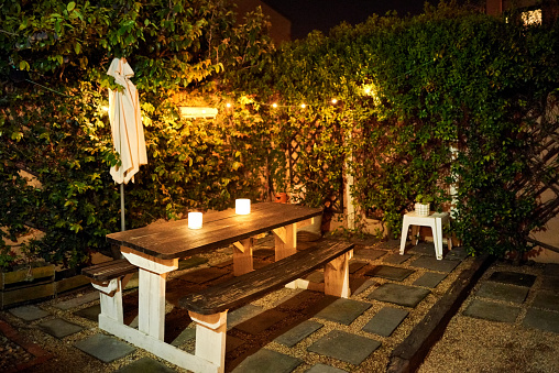 Shot of wooden dining table with candle lights in backyard garden in evening