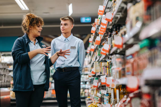 supermarktleiterin schult einen auszubildenden - auszubildender stock-fotos und bilder