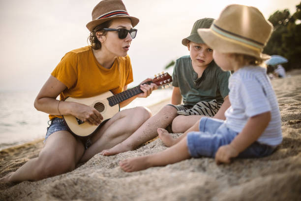 istock Boys and mum playing guitar at the beach 1329317662