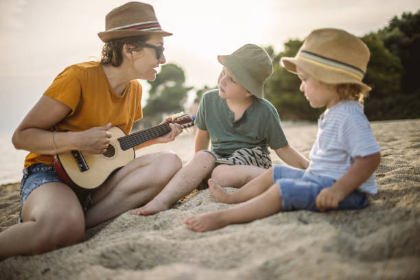 istock Boys and mum playing guitar at the beach 1329317808