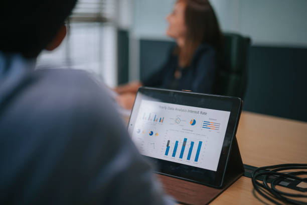 istock digital tablet with stock exchange data, Asia white collar worker video conference videocall with staff meeting discussion In the Conference Room Board of Directors Have Video Call with Investor. Business Meeting with Mergers and acquisitions 1329317975