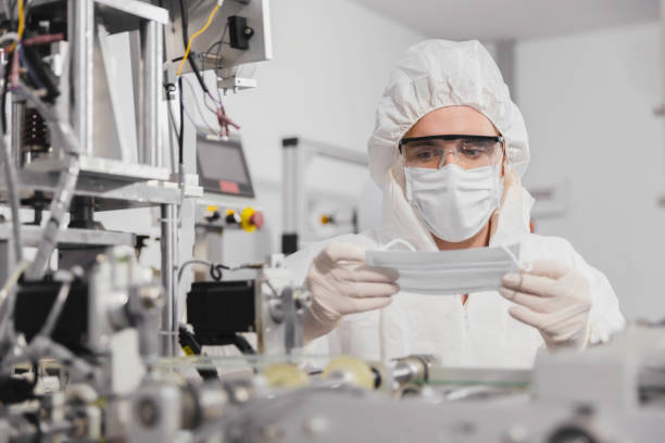 istock Technician or engineer in PPE working checking mask production at clean factory or laboratory, Face mask manufacturing production automation or quality concept 1329319017