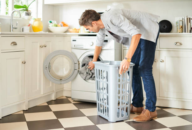 istock Young man loading a washing machine in his kitchen with clothing 1329320172