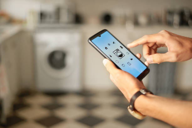 hombre que enciende su lavadora inteligente con una aplicación en su teléfono - equipment housework remote domestic kitchen fotografías e imágenes de stock