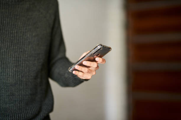 istock Young man standing outside and text messaging on his cellphone 1329320689