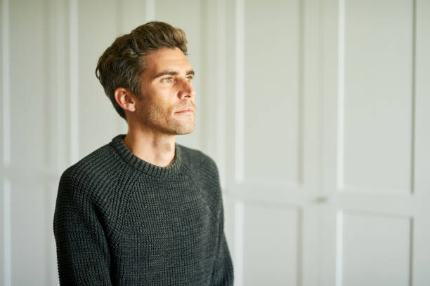 istock Young man standing alone at home and looking deep in thought 1329320713