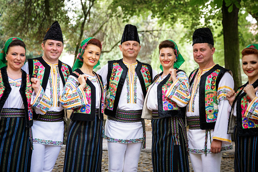 Deva, Romania - 16 July, 2021: a group of young traditional Romanian dancers wearing the traditional white costumes with intricate embroidery. They have just performed in a local park.