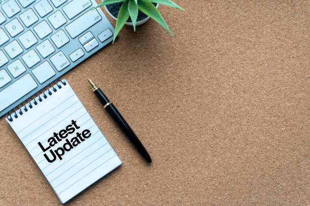 LATEST UPDATE text with notepad, decorative plant, keyboard and fountain pen on wooden background
