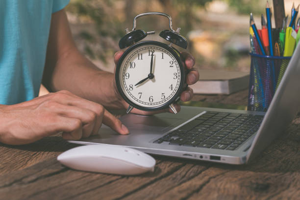 istock The hand holding the clock is at the work desk. 1329327912