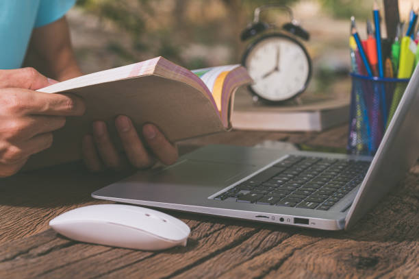 istock A person reading a book in front of a computer 1329327914