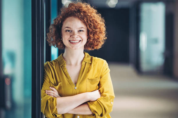 Smiling young redhead businesswoman Portrait of a young businesswoman standing in the office red hair stock pictures, royalty-free photos & images