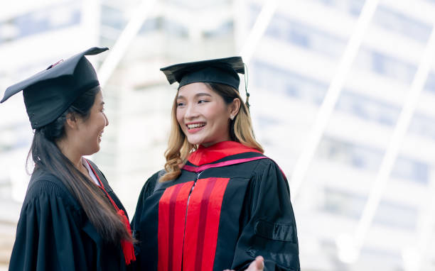 istock Two asian female successful students wearing uniform, cap and smiling with happiness after graduation. Education and Scholarship Concept. 1329331392