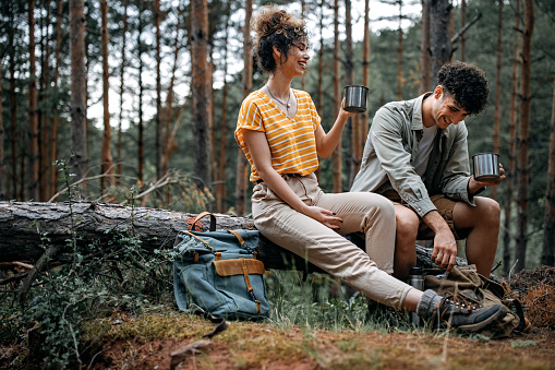 Young people taking a break for coffee while hiking through the forest.