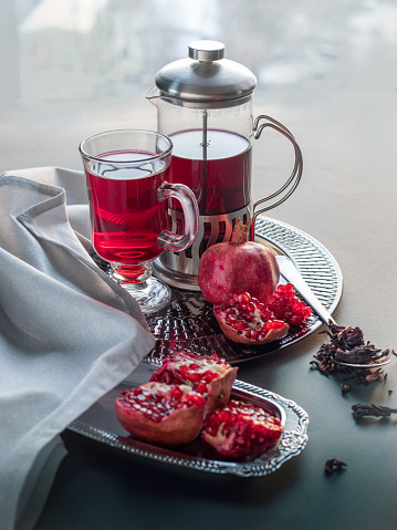 Turkish pomegranate tea in a teapot and  cup , whole pomegranates, pomegranate halves  and raw tea brew on a gray background.   Red pomegranate tea.   Healthy drinks.   Vegetarian food.  Alternative caffeine free drinks.   Herbal teas.