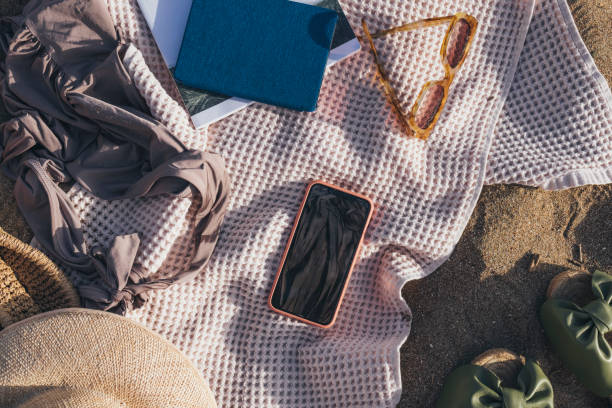 istock Ready for the Seaside: Beach Essentials Still Life on Sand Including a Smartphone 1329334391