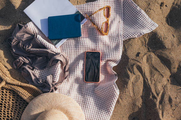 istock Ready for the Seaside: Beach Essentials Still Life on Sand Including a Smartphone 1329334392