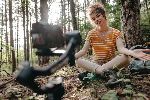 Influencer vlogging while spending time alone in forest.