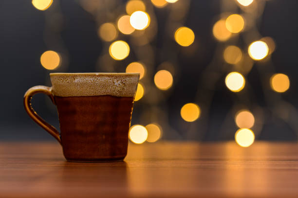 istock The coffee mug is on the desk. Orange bokeh lights backdrop 1329338636