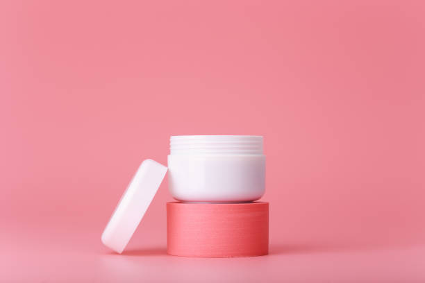 istock Opened cosmetic jar on pink pedestal on pink background 1329338813
